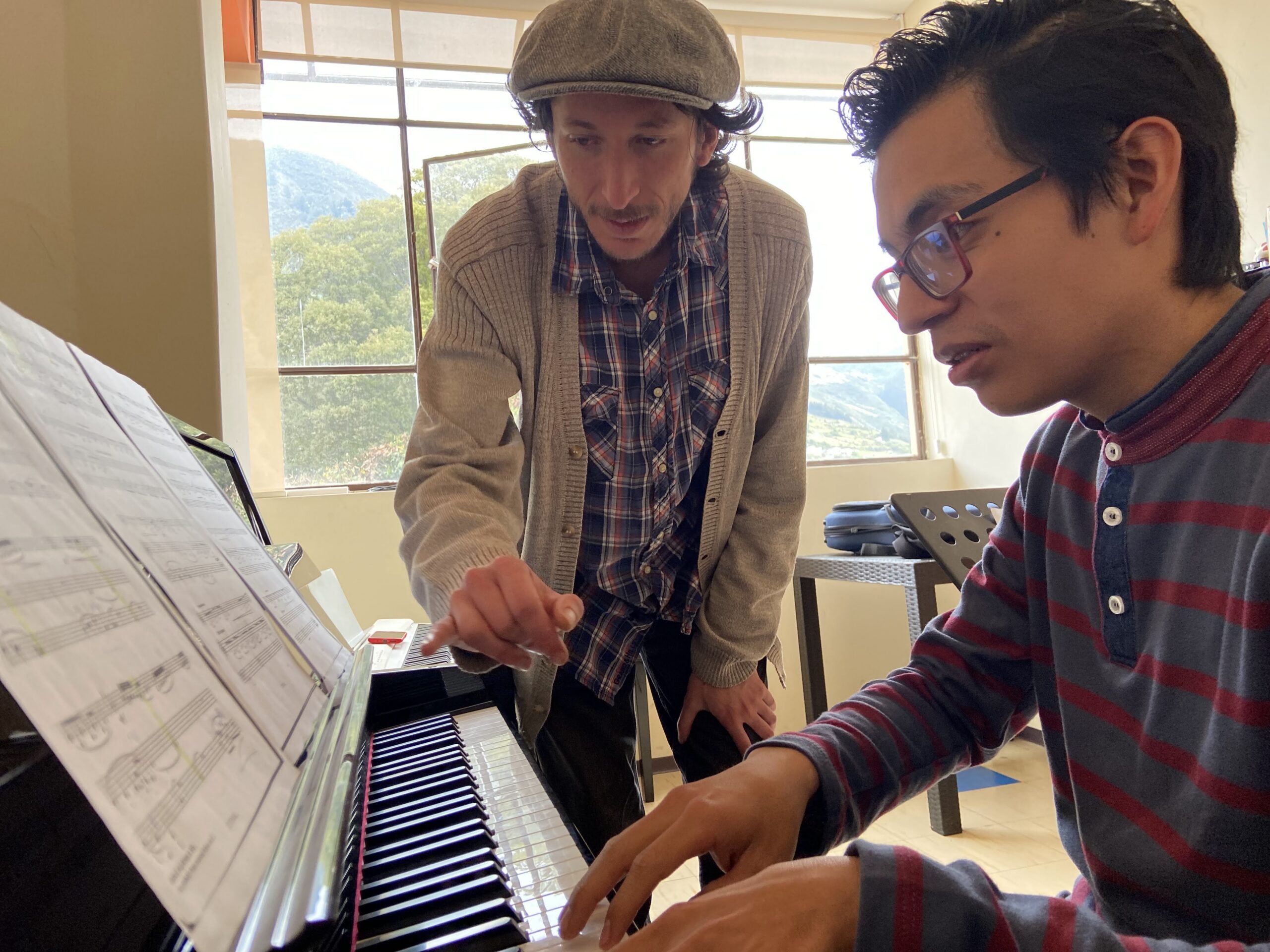 Profesor dando clases de piano a estudiante