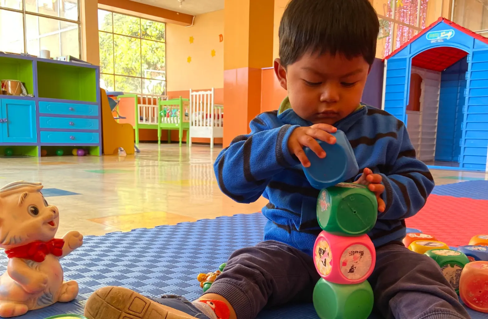 Niño pequeño jugando con bloques de colores en un aula de Educación Inicial del ISP INEPE.