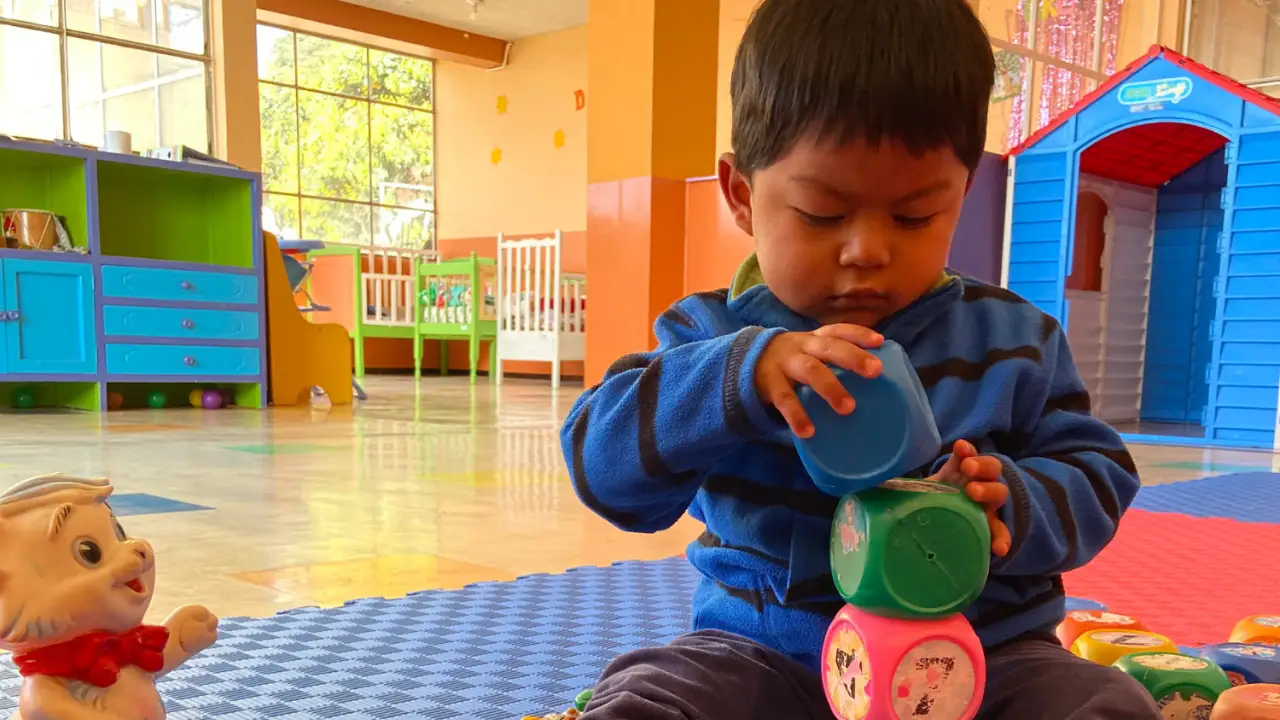 Niño pequeño jugando con bloques de colores en un aula de Educación Inicial del Instituto INEPE.